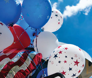American Flag flying with red white and blue party balloons